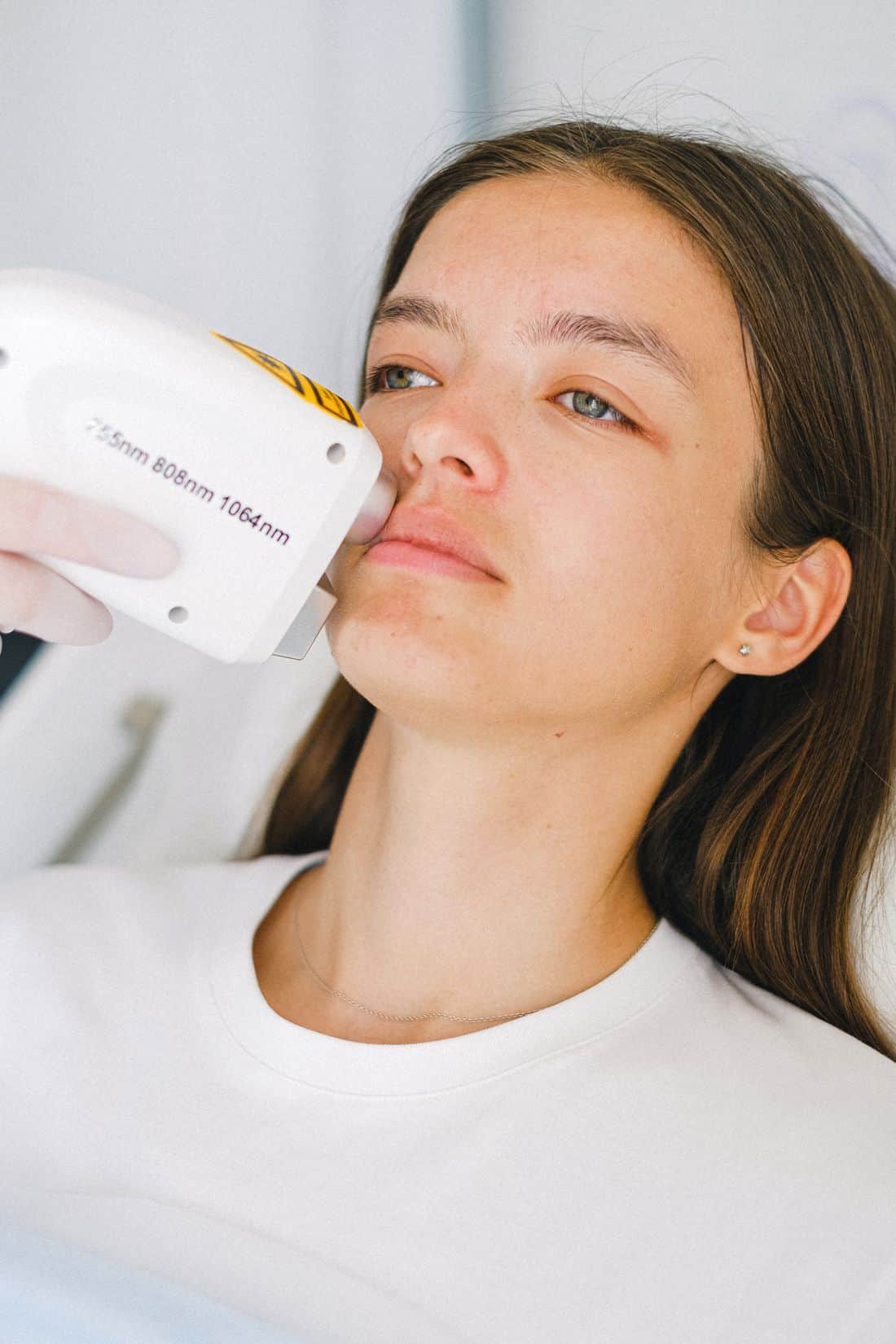 A laser handpiece held to a client's cheek during a facial laser session