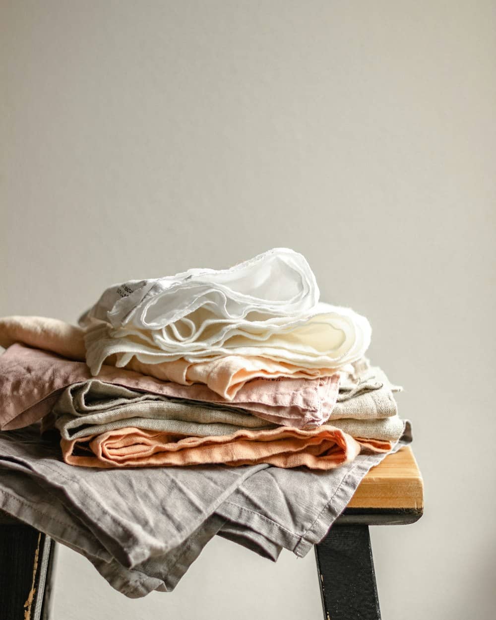Folded linens in warm neutral tones on a wooden stool at the studio