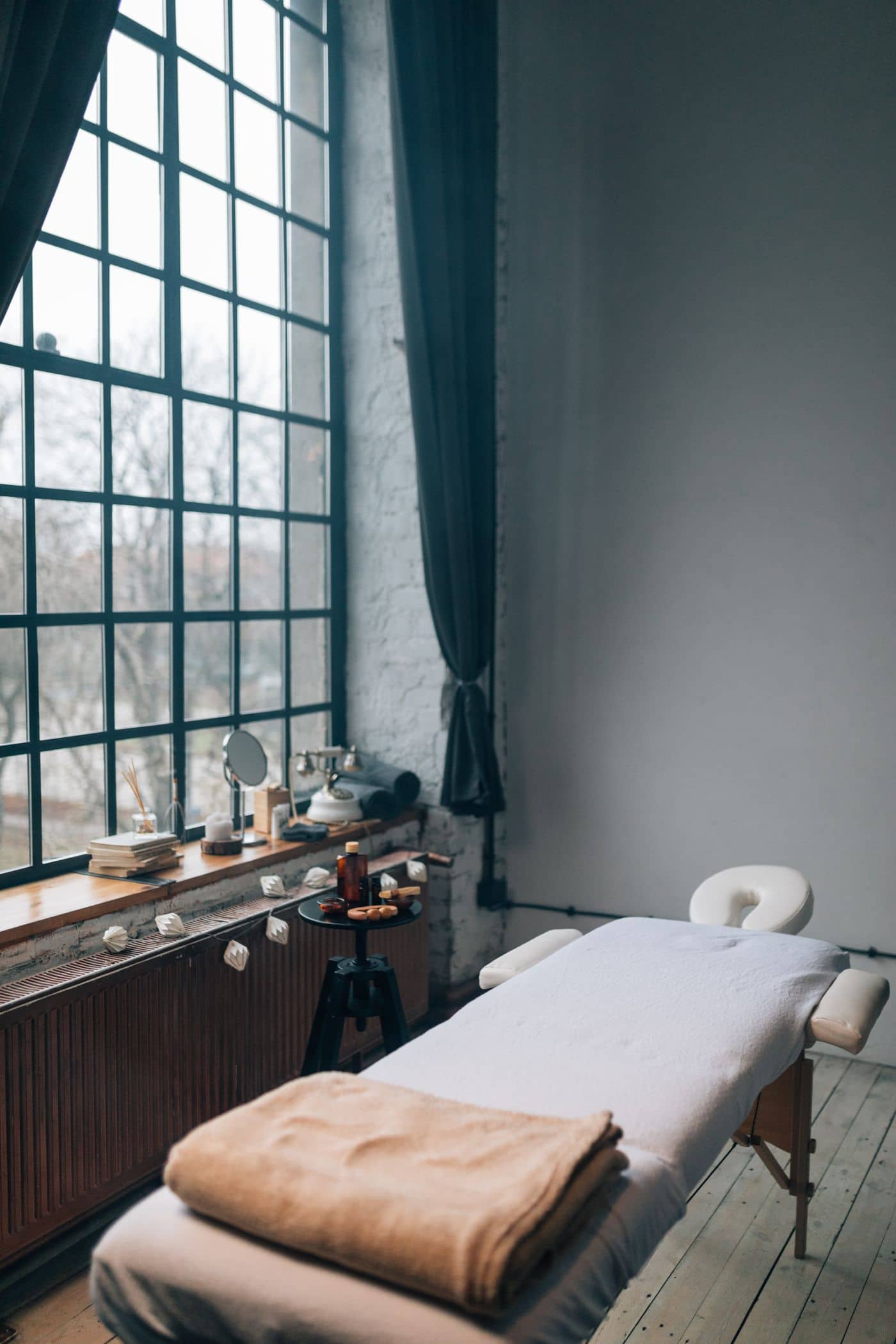 A treatment room at the Solene studio — tall steel-framed window, wooden sill, and soft natural light